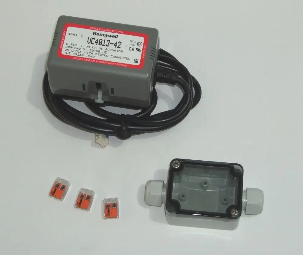 Honeywell UC4013-42 mit Anschlusskabel, umgeben von drei Sicherungen und einem grauen Gehäuse. Produkt dient vermutlich zur Ansteuerung eines Heizungsventils.
